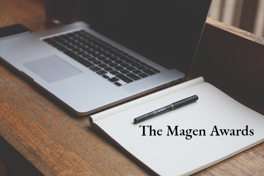 The Magen Awards. Image is of a desk with an open laptop and a notebook with a pen. The Magen Awards